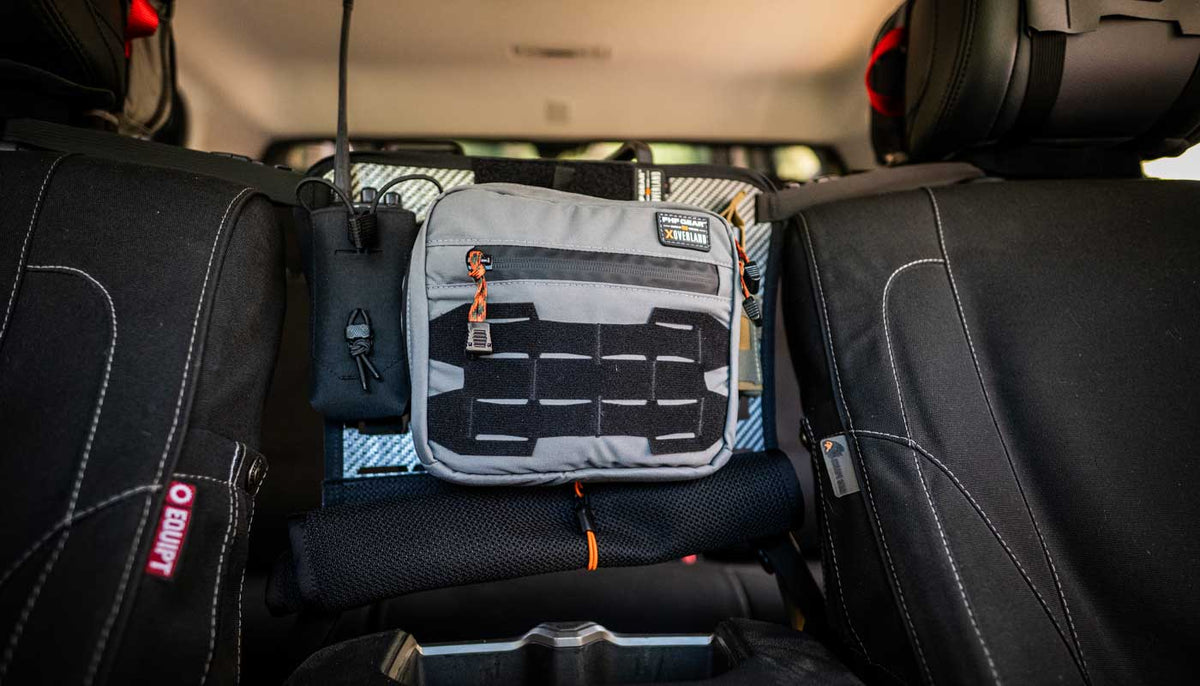 Grey and black modular organizing system hung between to truck seats.