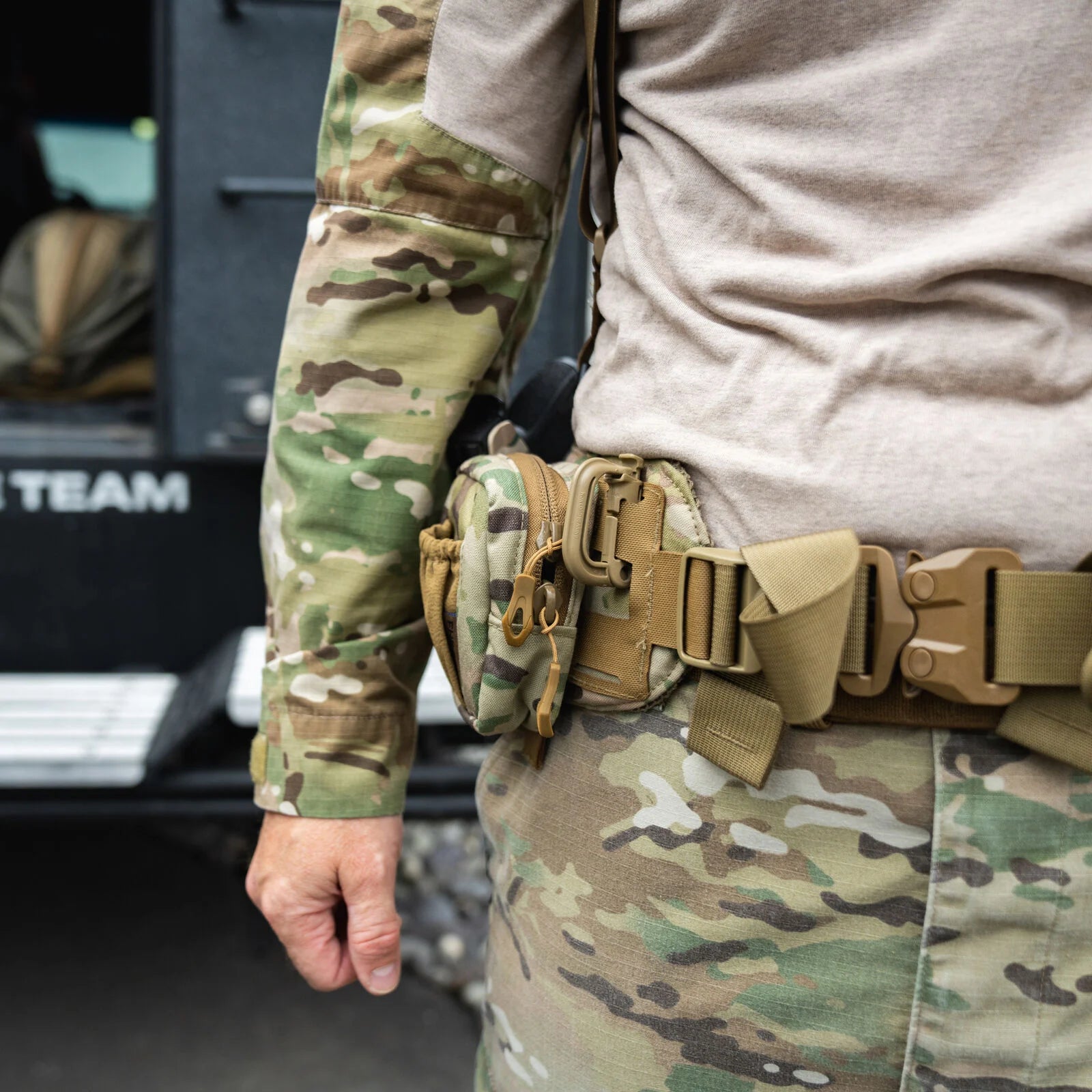 Multicam tactical pouch attached to a tan tactical belt with a quick-release buckle.