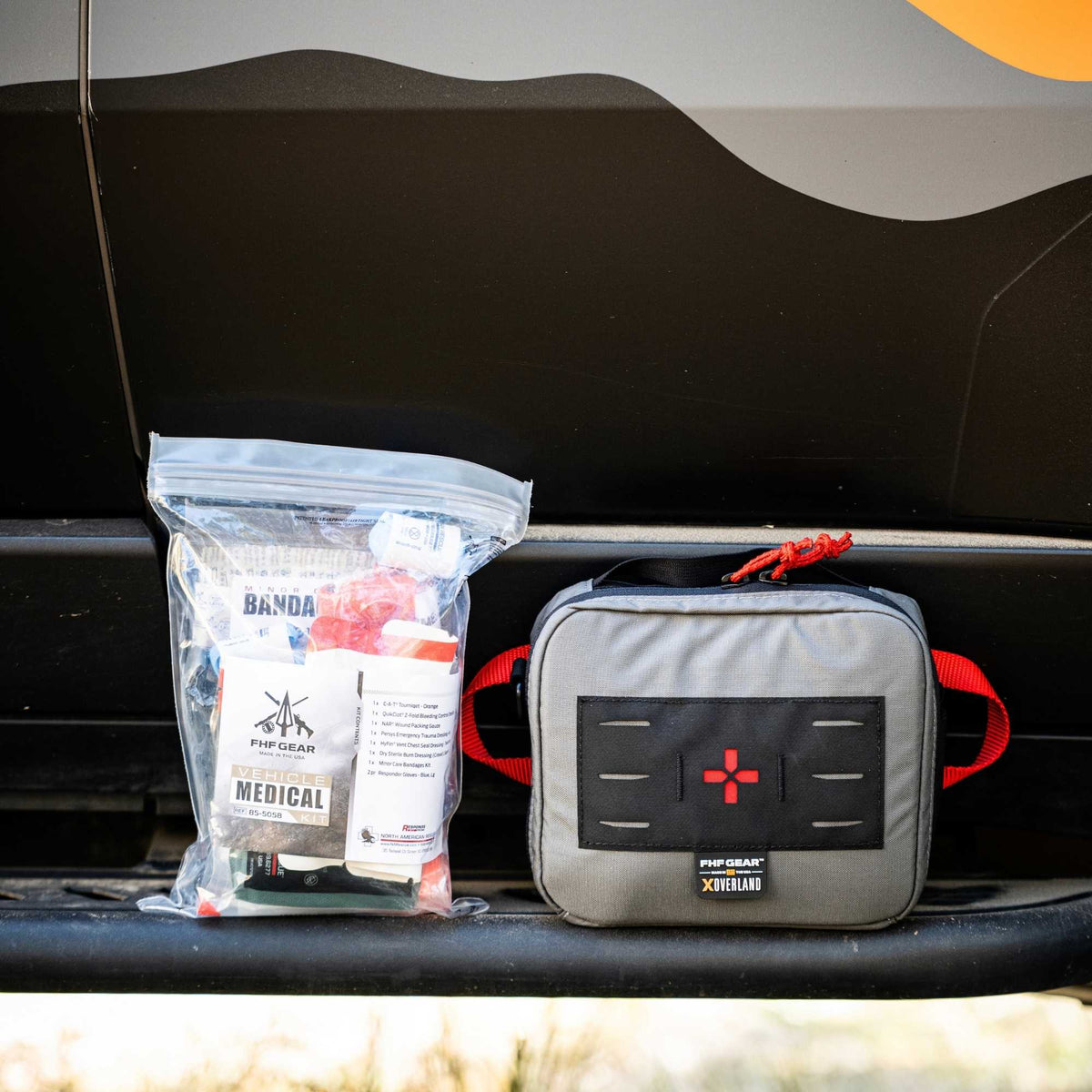 Flex Med Kit in grey and NAR Vehicle Med Kit in front of a van front door.