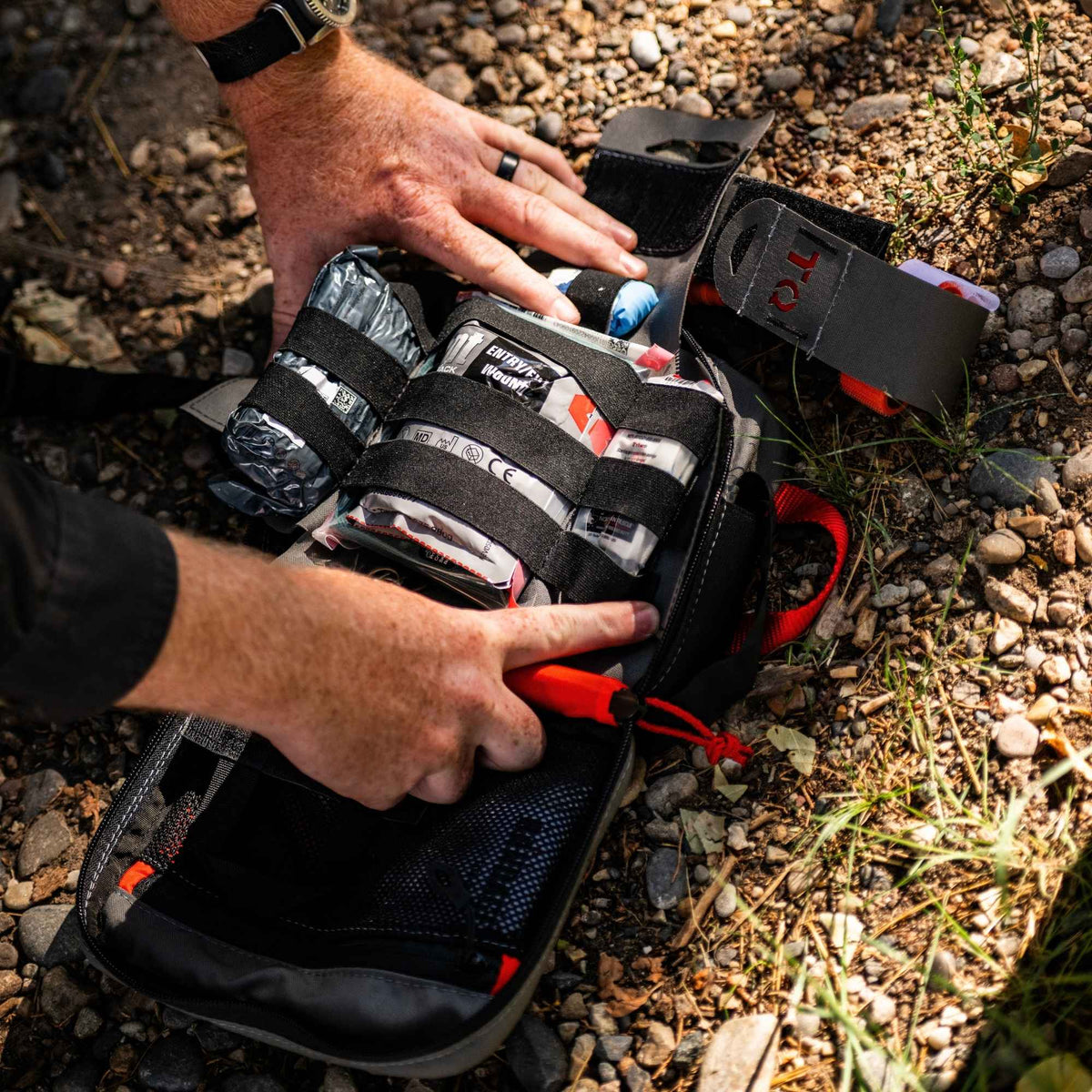 Man grabbing medical inputs from a med kit on the ground.