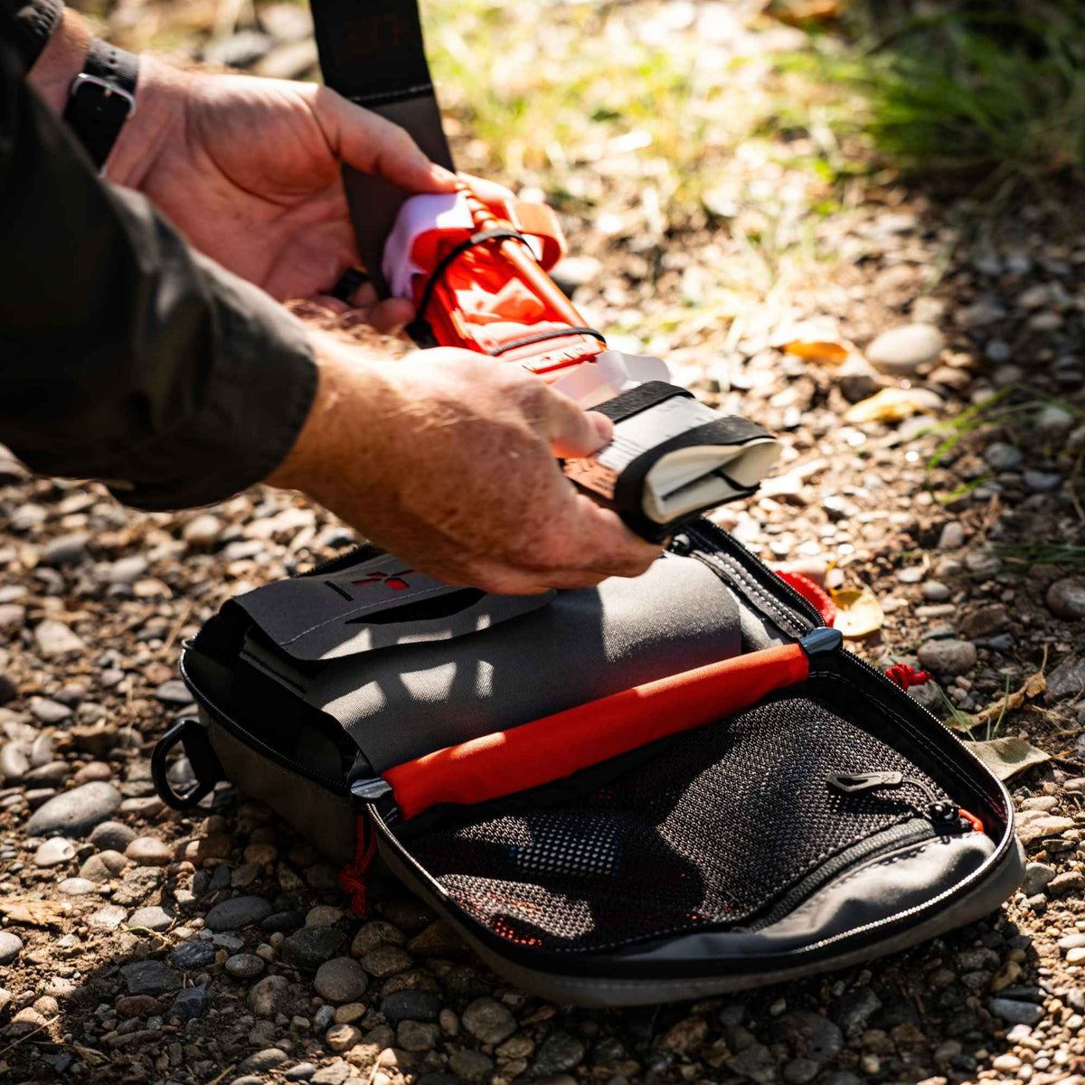 Man holding medical inputs and below on the ground is a med kit pouch open.