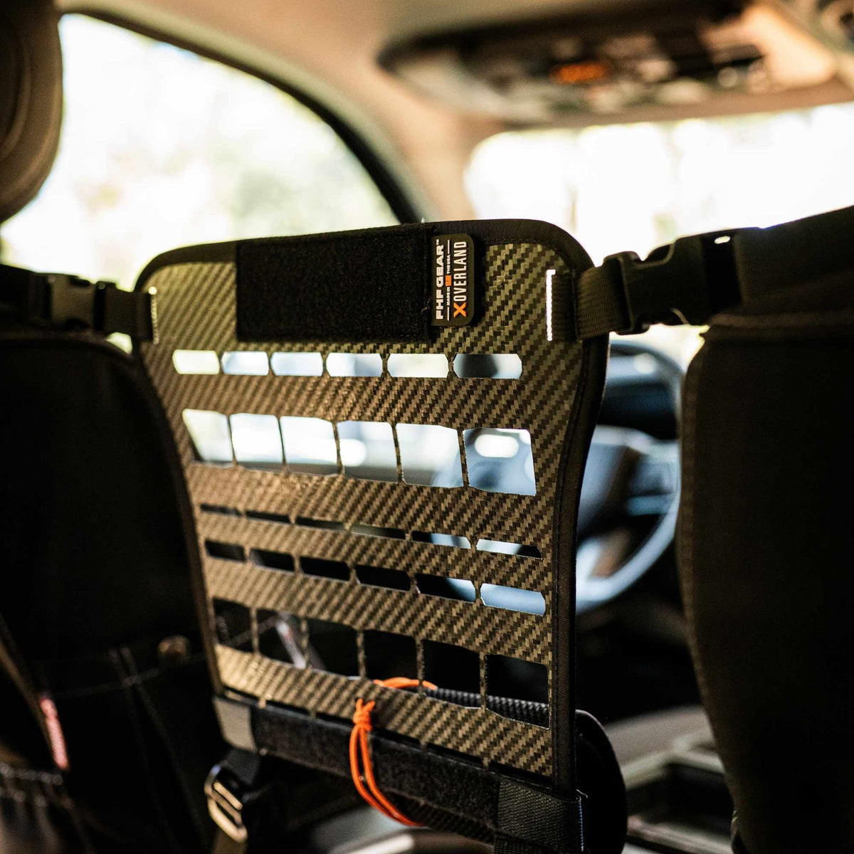 The Bulkhead mounted between two front van seats with straps holding to the headrests and an orange cord tied in the bottom grid.