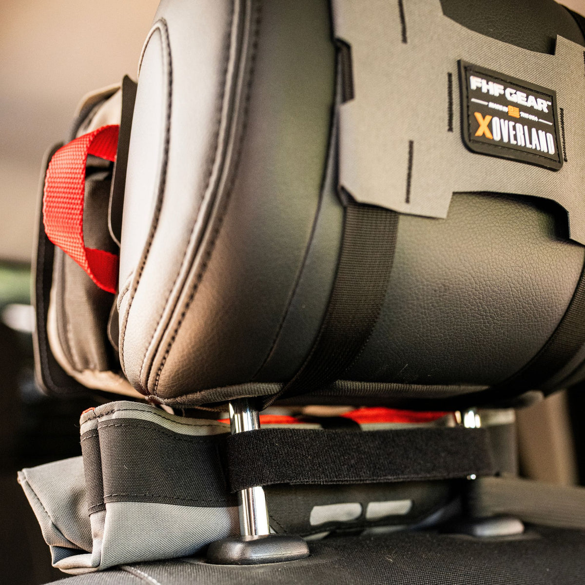 Grey medical kit on a headrest with an orange strap on the side, and showcasing FHF GEAR XOVERLAND branding.