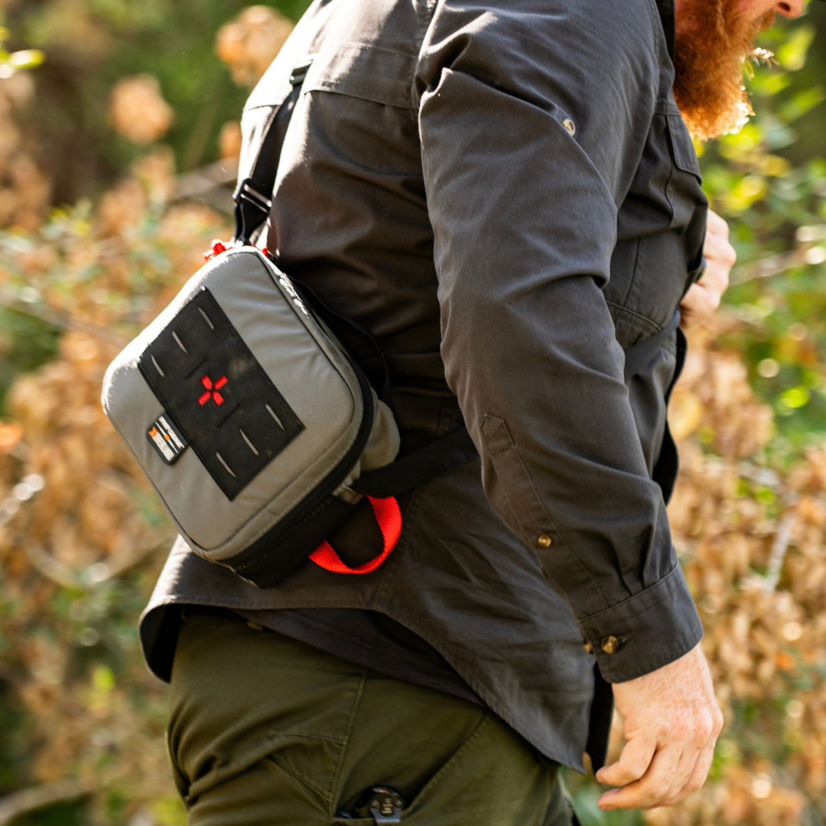 Man carrying a grey medical kit hanging from a shoulder strap.
