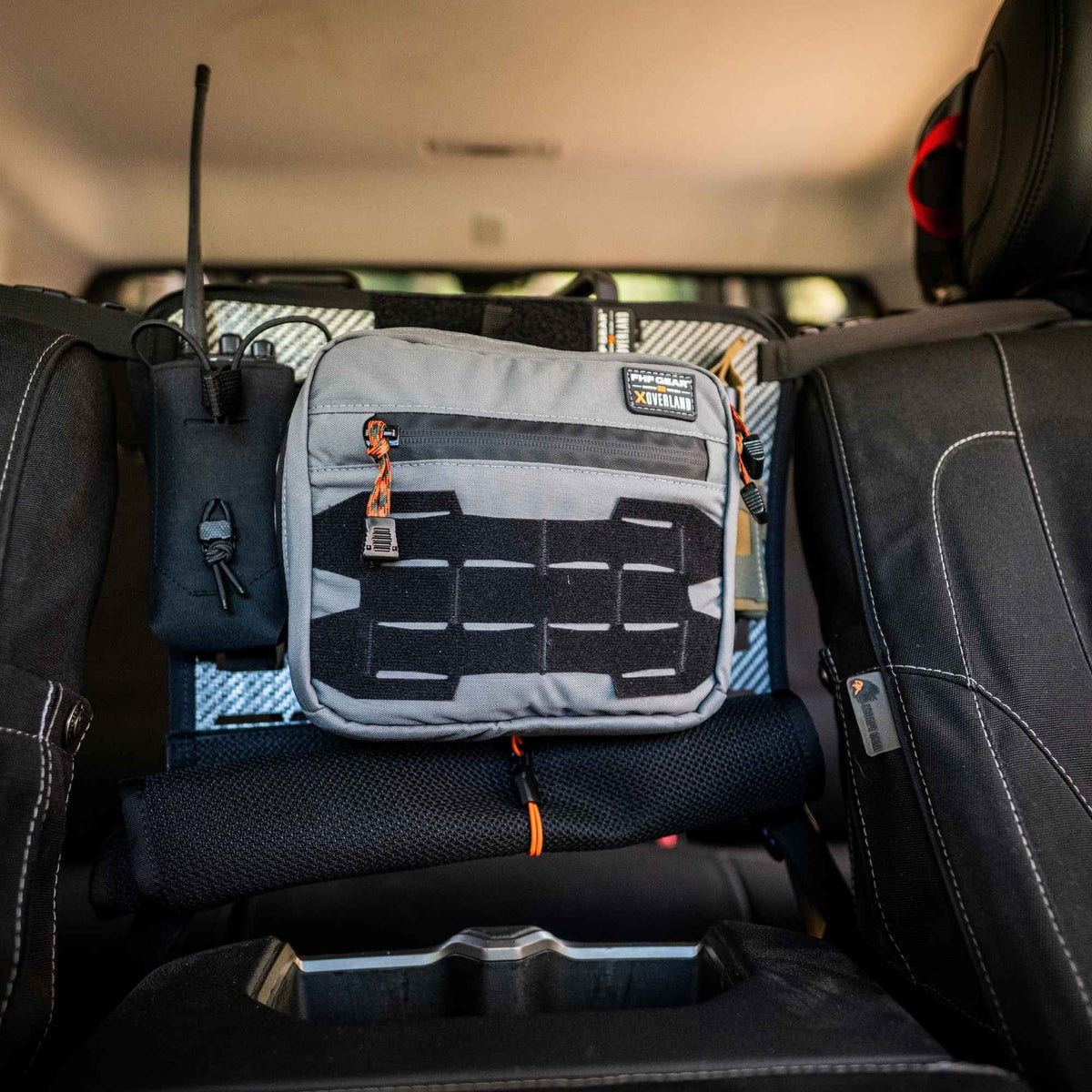Grey Waypoint GP Pouch mounted between two black front seats, it has a radio beside it.
