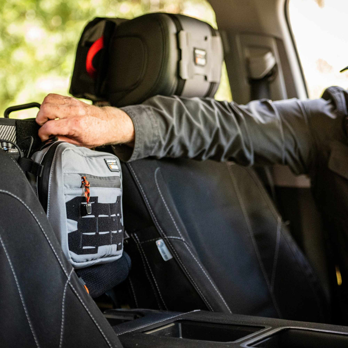 Man mounting a grey Waypoint GP Pouch between two front seats.
