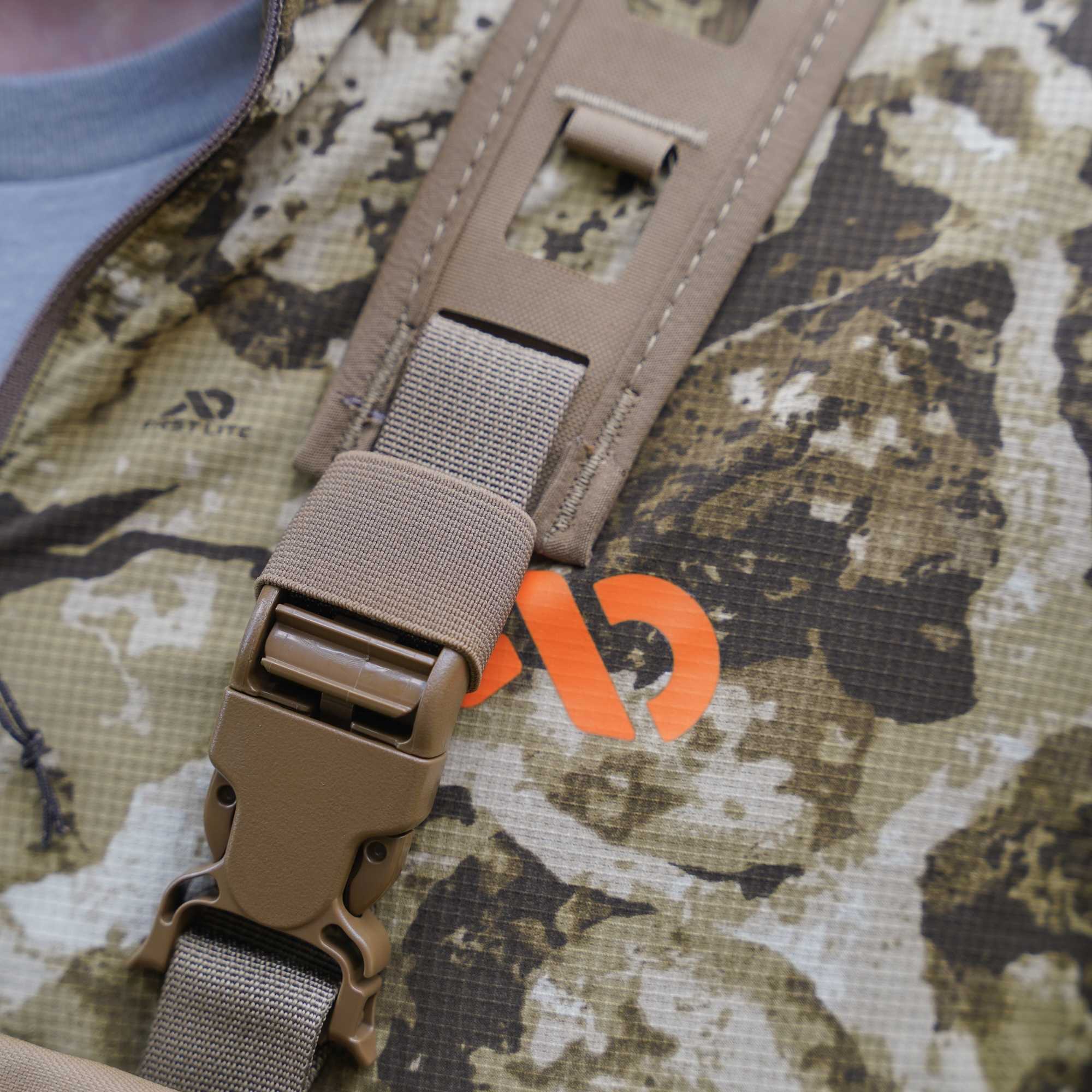 Padded tan hunting gear with tan mesh, buckles over a camo jacket.