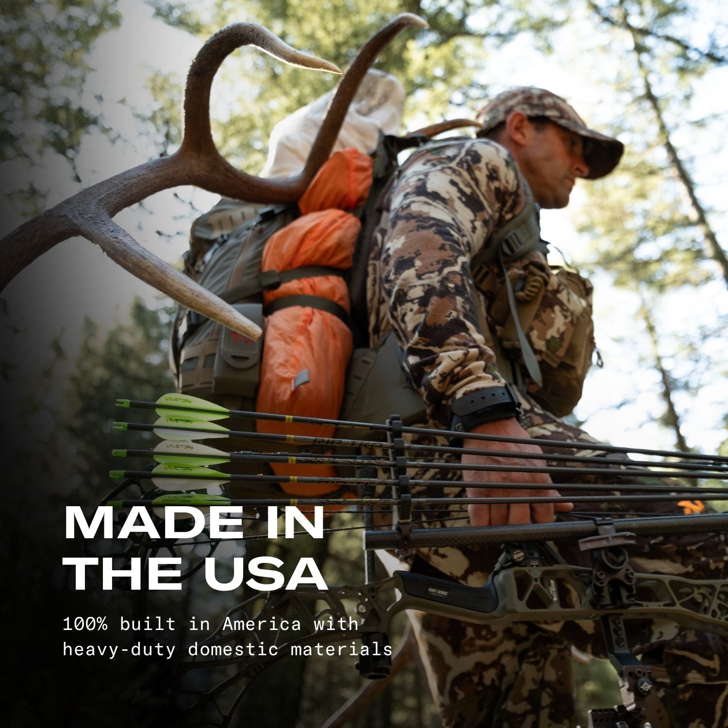A man in camouflage hunting apparel stands in a forest with a compound bow, arrows, and a large deer antler rack on his back. Text on the image reads 'MADE IN THE USA' with additional text below about domestic materials.