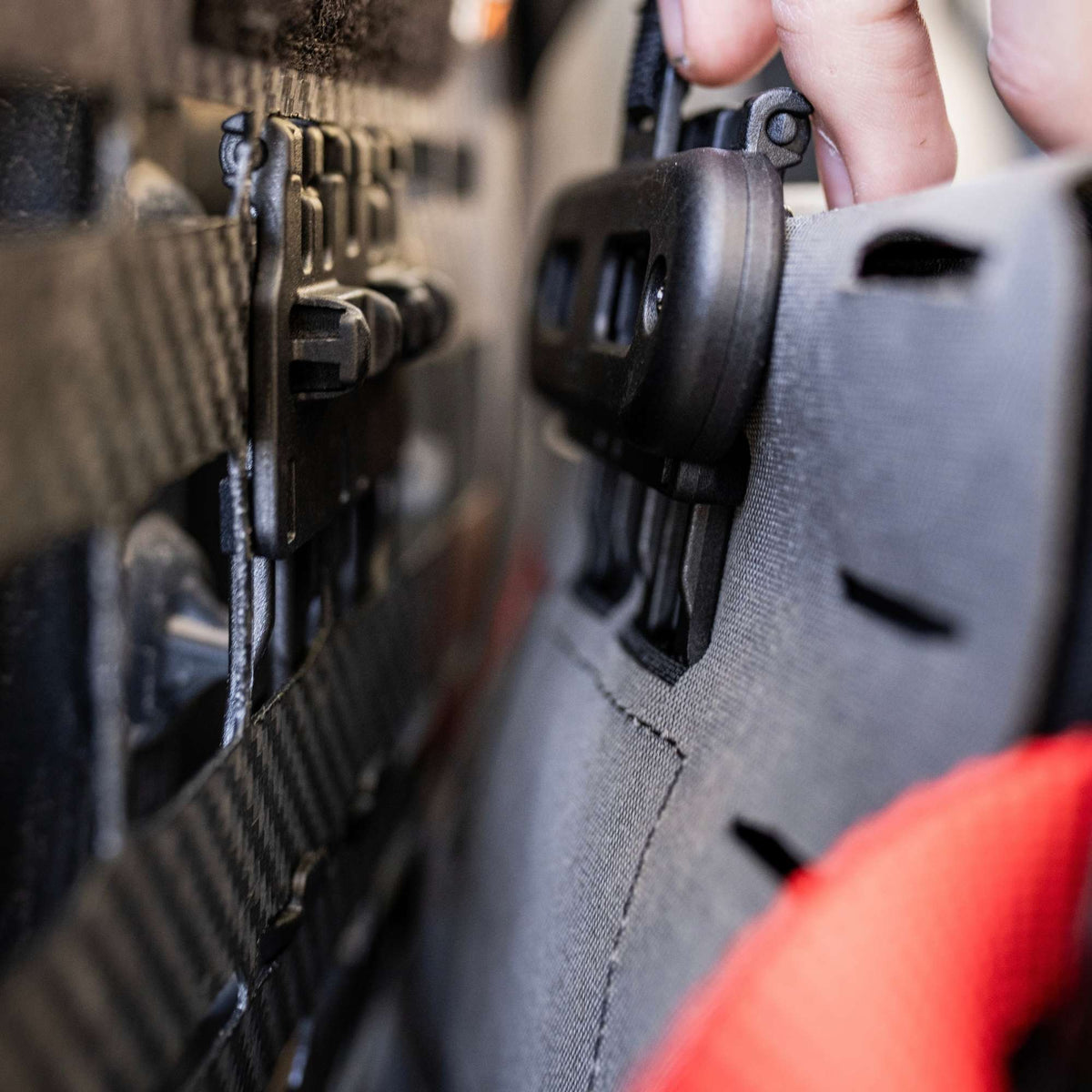 Man mounting a grey pouch to a multi-point webbing strap with a to a black Snapcor buckle.